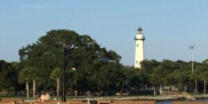 Lighthouse and wooden pier over water.