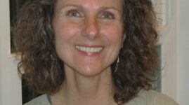 Smiling woman with curly hair indoors.