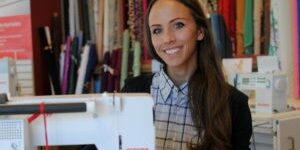 Woman smiling at sewing machine in store.