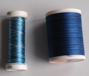 Two spools of blue thread, one light and one dark.