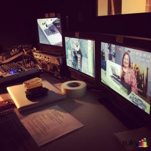 Video editing workstation with multiple screens showing a female presenter.
