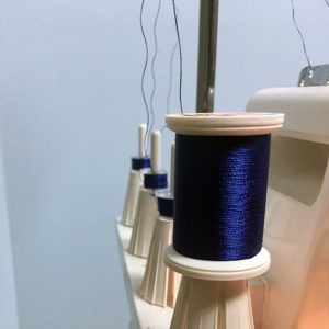 Close-up of blue thread spools on a sewing machine.