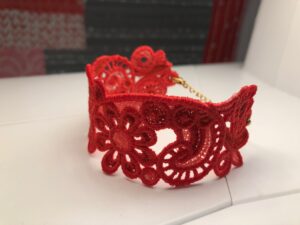 Intricately designed red lace bracelet with floral patterns.