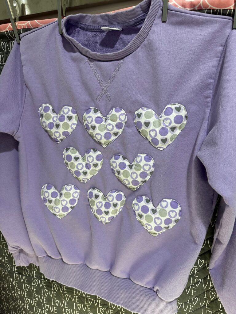 finished Puffy Heart applique sweatshirt hanging on wall