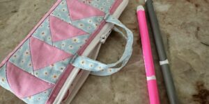 Quilted pencil case with pens on table.