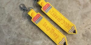 Yellow pencil-shaped keychains on marble surface.