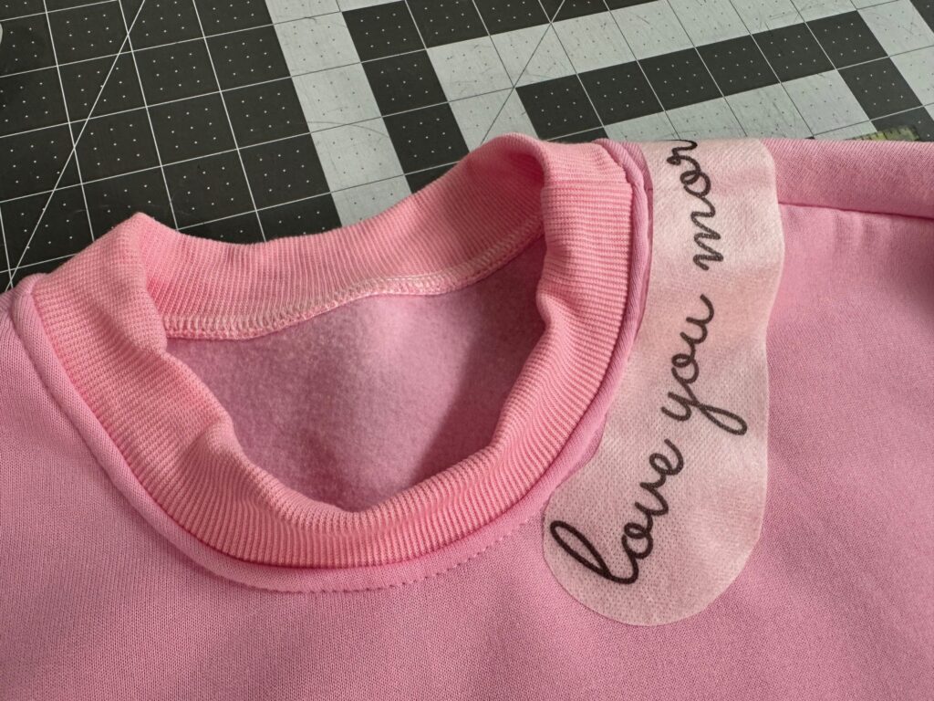 Stick n Stitch transfer placed on sweatshirt neckline