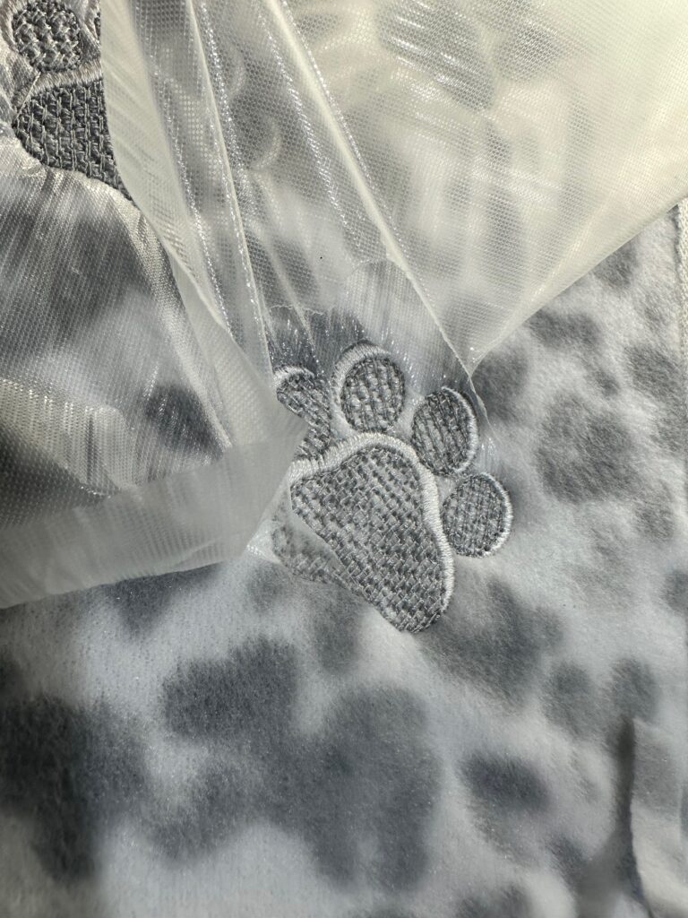 Smiling woman with short brown hair wearing a black top and pearl necklace.