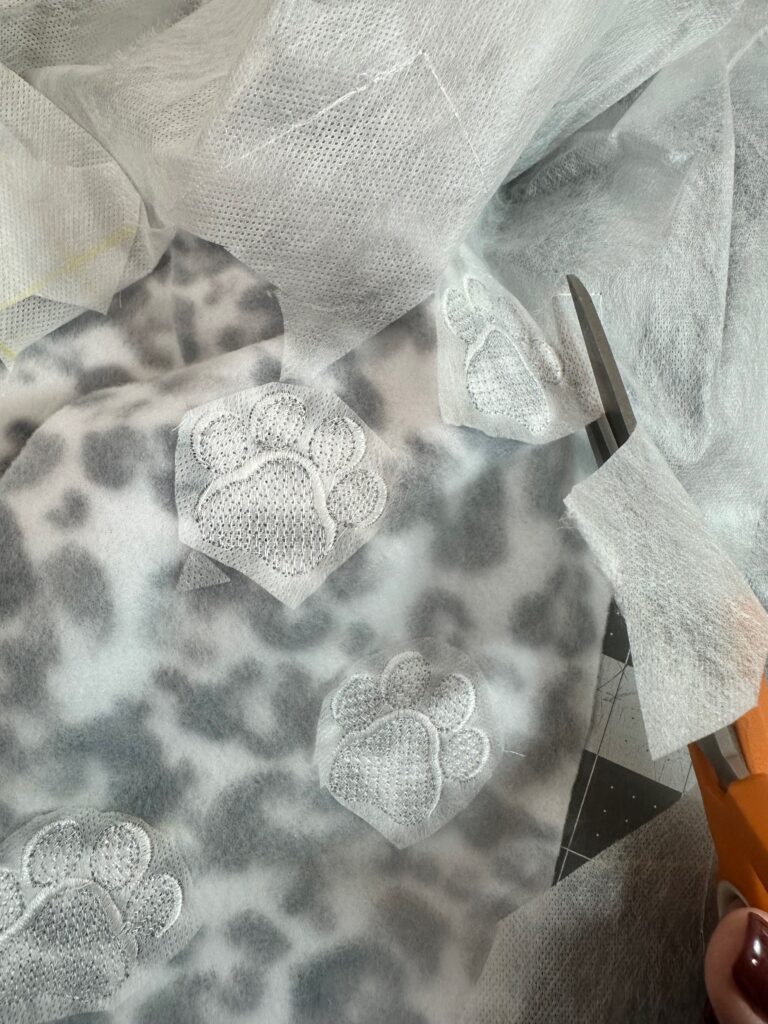 Smiling woman with short brown hair wearing a black top and pearl necklace.