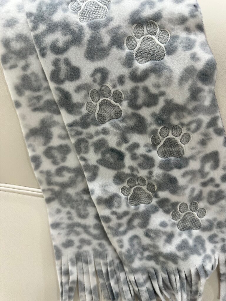 Smiling woman with short brown hair wearing a black top and pearl necklace.