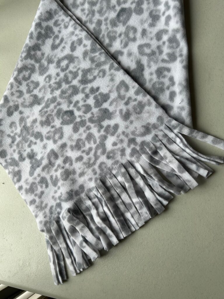 Smiling woman with short brown hair wearing a black top and pearl necklace.