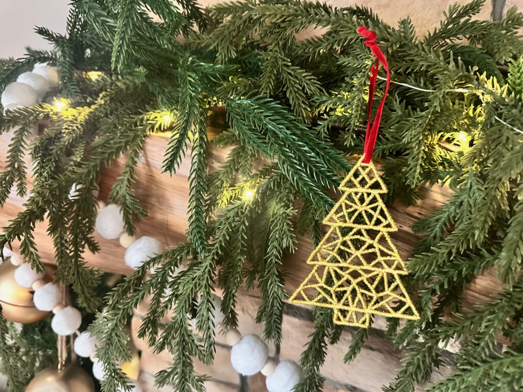FSL metallic ornament hanging on branch with Christmas lights