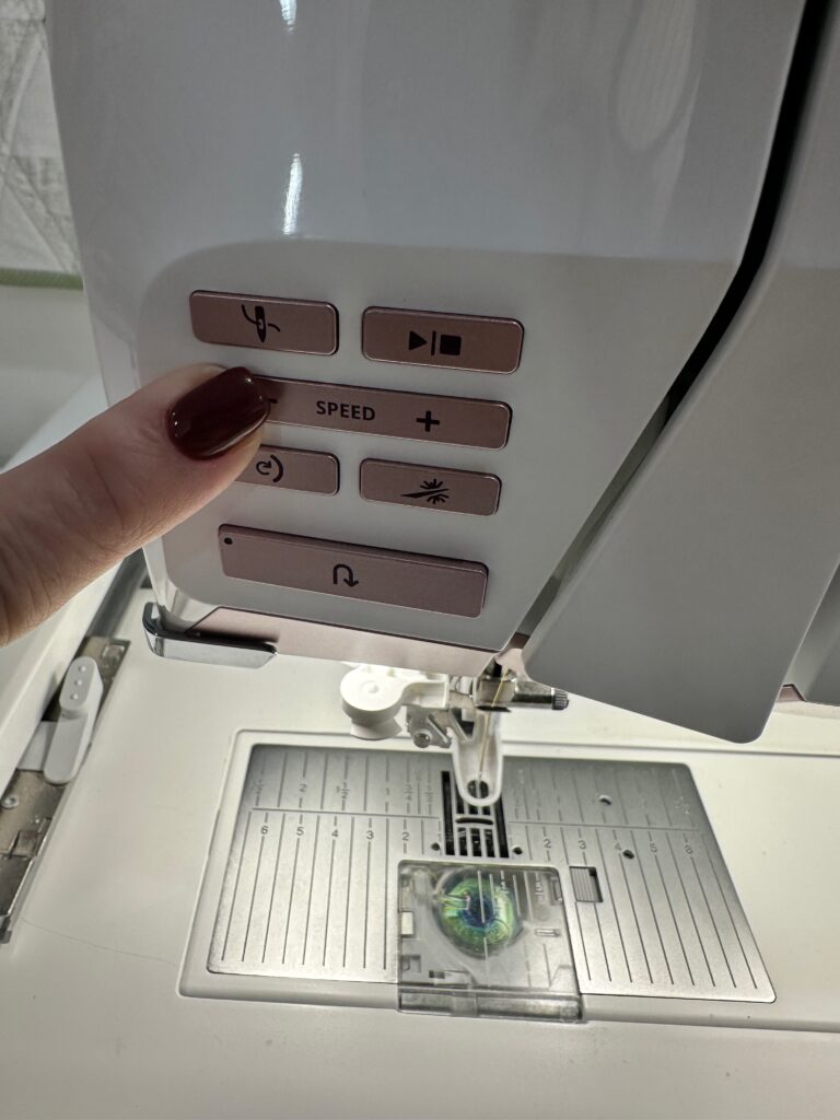 A hand adjusting sewing machine stitch settings.