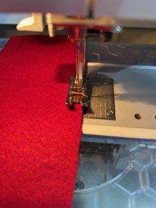 Close-up of a sewing machine stitching red fabric.