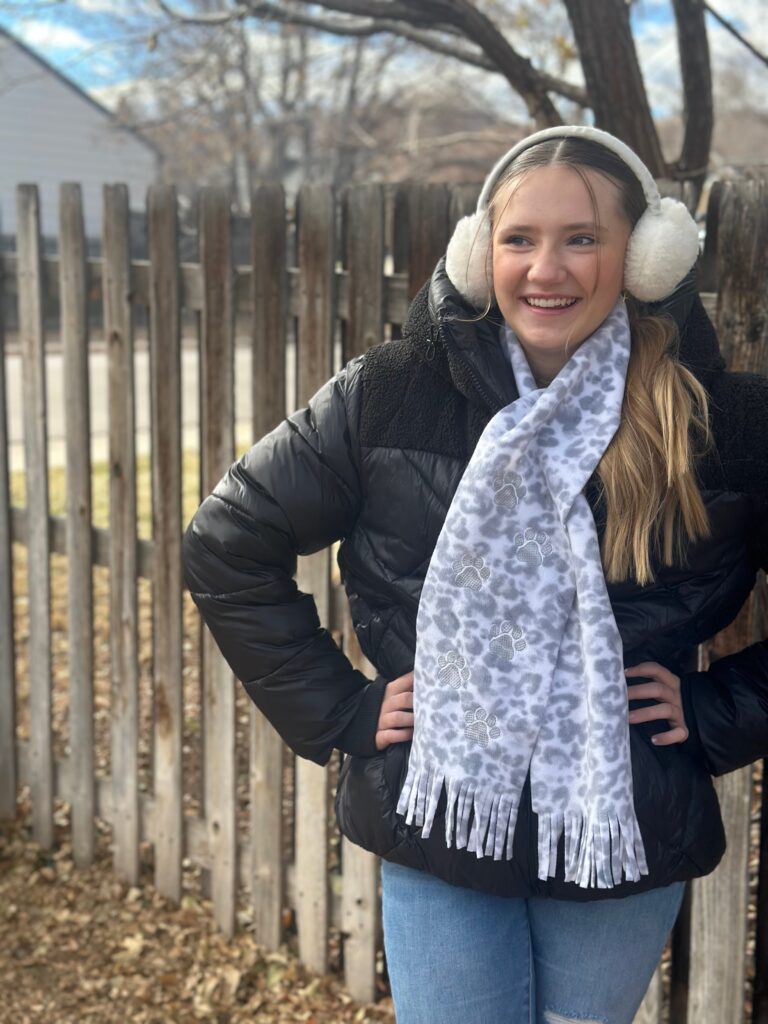 Smiling woman with short brown hair wearing a black top and pearl necklace.