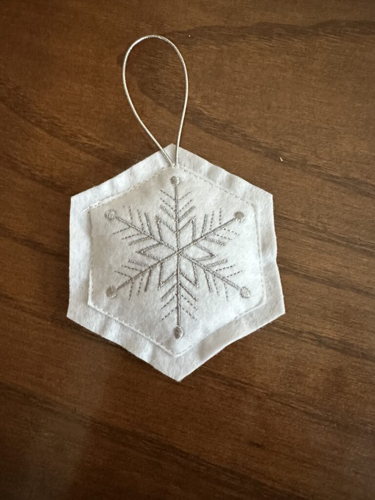 finished white felty ornament with silver stitching