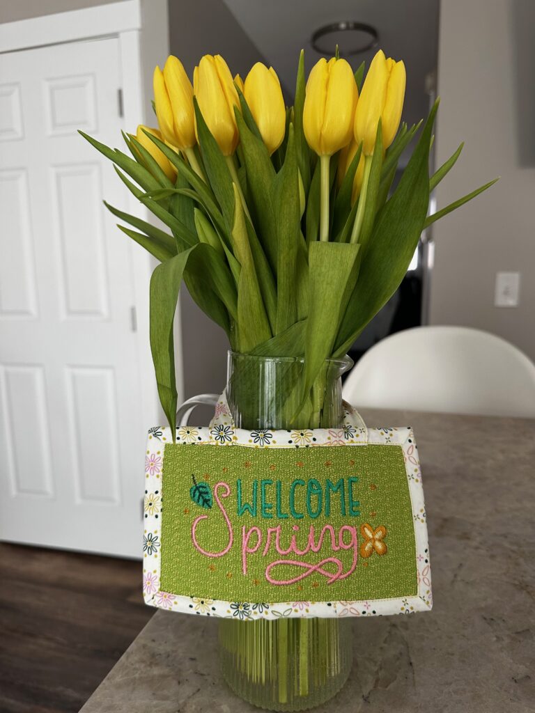 welcome spring sign with tulips in vase