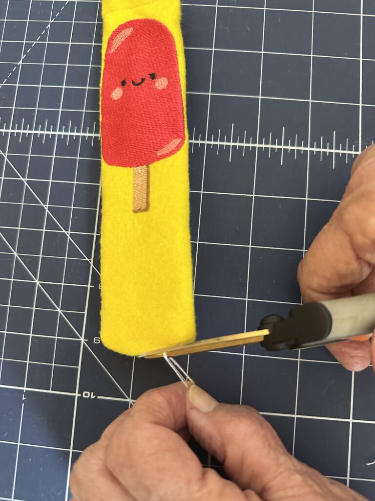 snipping off floss at Koozie lower edge