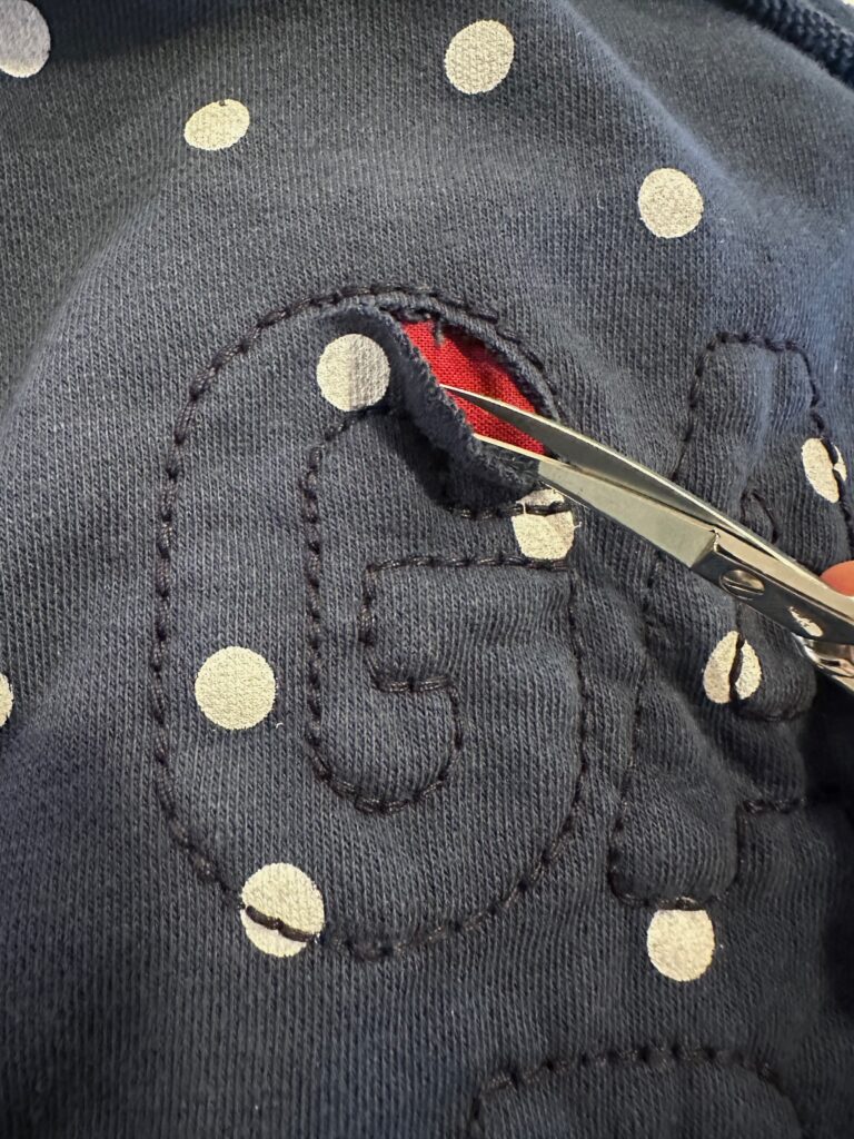 cutting sweatshirt layer to reveal appliqué fabric